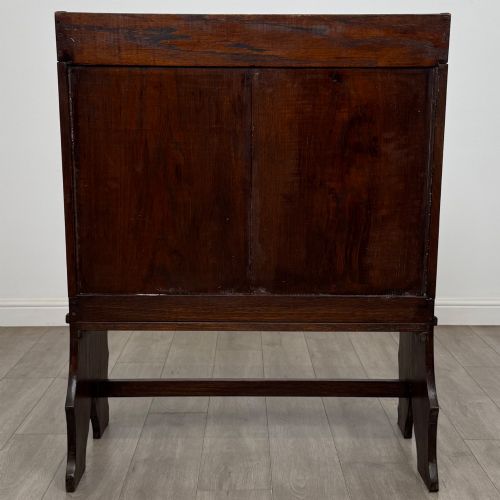 fig 4. A dark oak high-back settle featuring a floral relief carving along the top rail, shaped side panels, and a stretcher base.