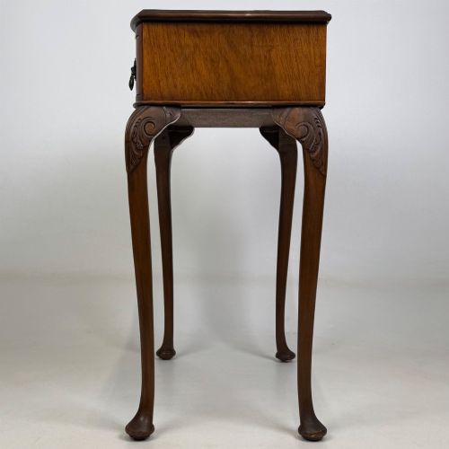 fig 2. An Edwardian side table crafted from warm brown figured walnut featuring a single drawer with ornate brass handles and carved cabriole legs.