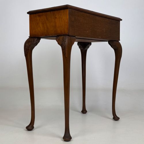 fig 3. An Edwardian side table crafted from warm brown figured walnut featuring a single drawer with ornate brass handles and carved cabriole legs.