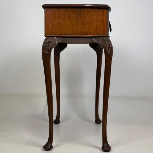 fig 6. An Edwardian side table crafted from warm brown figured walnut featuring a single drawer with ornate brass handles and carved cabriole legs.