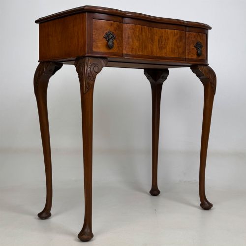 fig 7. An Edwardian side table crafted from warm brown figured walnut featuring a single drawer with ornate brass handles and carved cabriole legs.