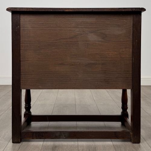 fig 5. A small warm brown carved oak cupboard with double doors featuring carved arches, iron hinges, turned legs, and a lower stretcher base.