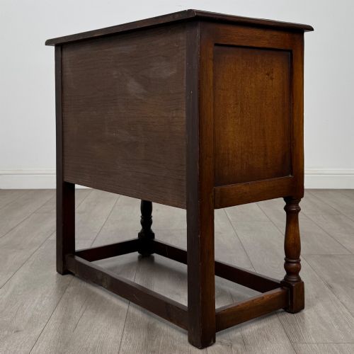 fig 6. A small warm brown carved oak cupboard with double doors featuring carved arches, iron hinges, turned legs, and a lower stretcher base.