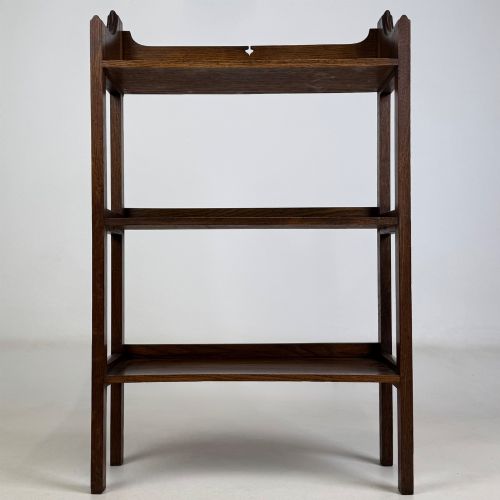 fig 1. An early 20th-century Arts and Crafts solid oak open bookcase featuring three fixed shelves and a shaped gallery backboard with a cutout heart motif.