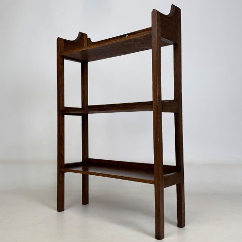 fig 2. An early 20th-century Arts and Crafts solid oak open bookcase featuring three fixed shelves and a shaped gallery backboard with a cutout heart motif.