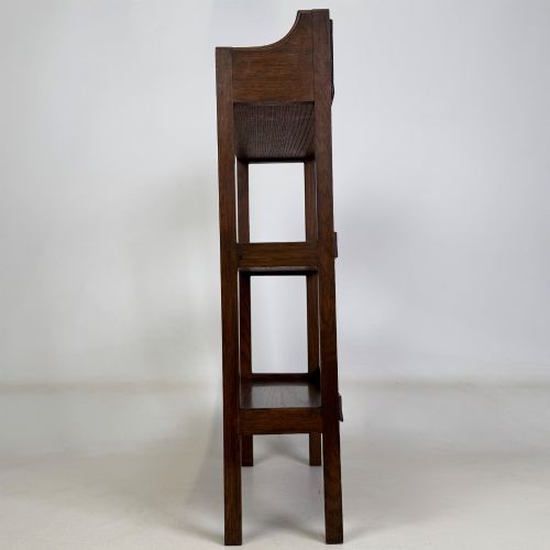 fig 3. An early 20th-century Arts and Crafts solid oak open bookcase featuring three fixed shelves and a shaped gallery backboard with a cutout heart motif.