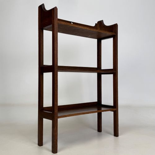 fig 8. An early 20th-century Arts and Crafts solid oak open bookcase featuring three fixed shelves and a shaped gallery backboard with a cutout heart motif.