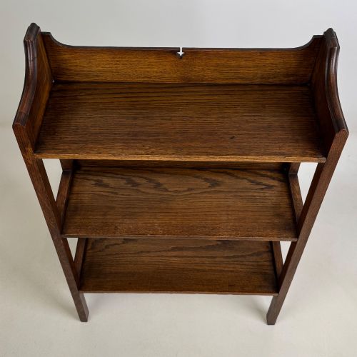 fig 9. An early 20th-century Arts and Crafts solid oak open bookcase featuring three fixed shelves and a shaped gallery backboard with a cutout heart motif.