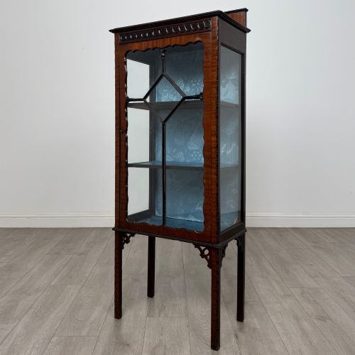 fig 2. A slender Edwardian mahogany glazed display cabinet featuring astragal door bars and a fabric-lined interior raised on square legs.