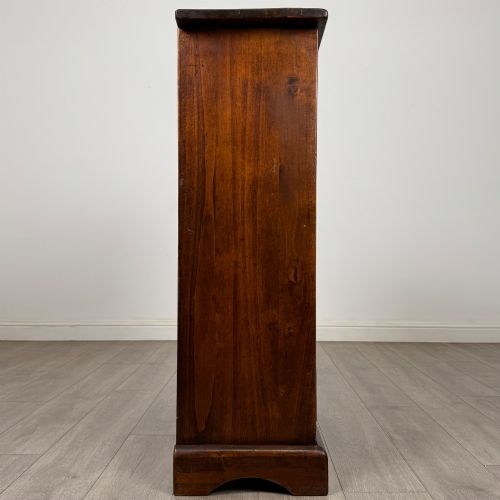 fig 6. A tall dark brown hardwood chest of drawers featuring five horizontal drawers fitted with metal ring pull handles.