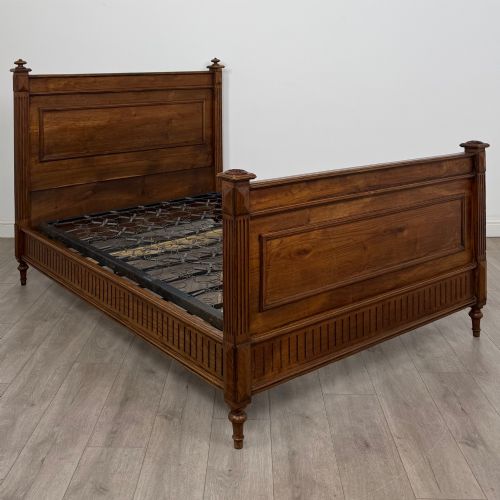 fig 1. A 19th-century French oak double bed frame featuring a raised panelled headboard and footboard flanked by fluted posts with turned finials.