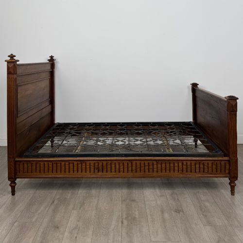 fig 2. A 19th-century French oak double bed frame featuring a raised panelled headboard and footboard flanked by fluted posts with turned finials.