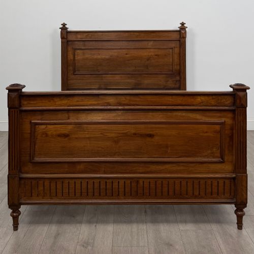 fig 3. A 19th-century French oak double bed frame featuring a raised panelled headboard and footboard flanked by fluted posts with turned finials.