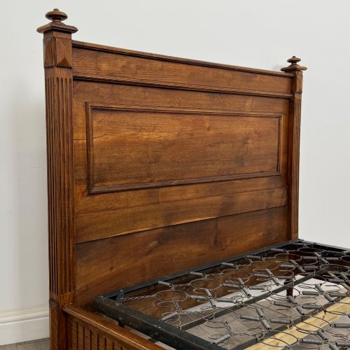 fig 4. A 19th-century French oak double bed frame featuring a raised panelled headboard and footboard flanked by fluted posts with turned finials.