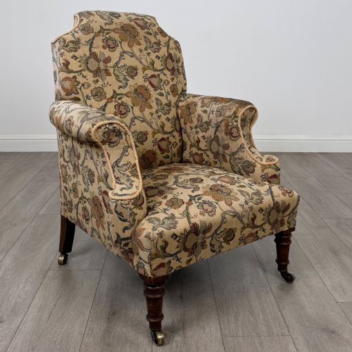 fig 6. A 19th-century wingback armchair upholstered in floral tapestry fabric with turned mahogany front legs on brass castors.