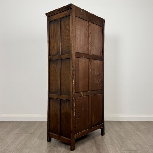 fig 4. A narrow twentieth-century dark oak single-door wardrobe featuring carved scrollwork panels, a decorative painted top frieze, and panelled construction.