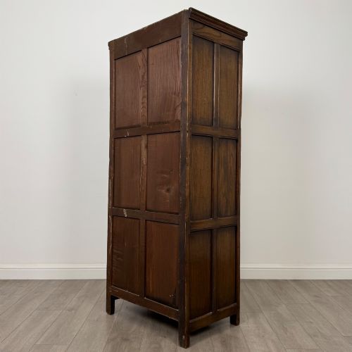 fig 6. A narrow twentieth-century dark oak single-door wardrobe featuring carved scrollwork panels, a decorative painted top frieze, and panelled construction.