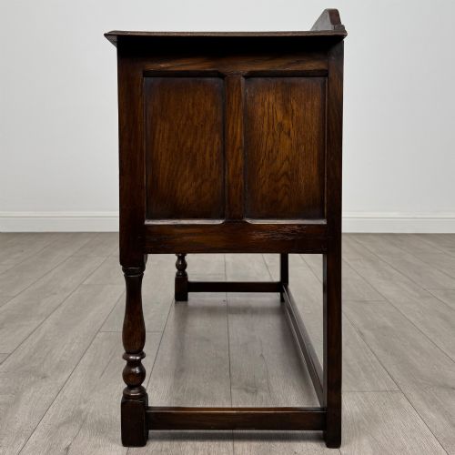 fig 2. A dark oak chest featuring two top drawers above one wide bottom drawer, resting on turned legs connected by a low stretcher frame.