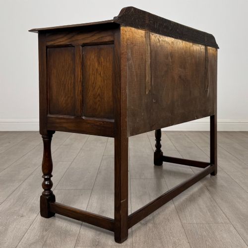 fig 3. A dark oak chest featuring two top drawers above one wide bottom drawer, resting on turned legs connected by a low stretcher frame.