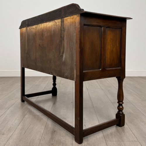 fig 5. A dark oak chest featuring two top drawers above one wide bottom drawer, resting on turned legs connected by a low stretcher frame.