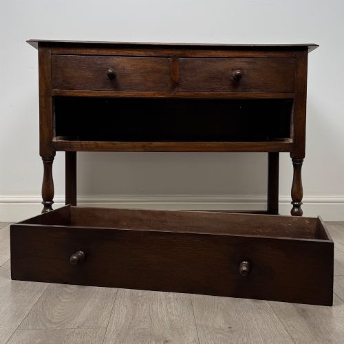 fig 9. A dark oak chest featuring two top drawers above one wide bottom drawer, resting on turned legs connected by a low stretcher frame.