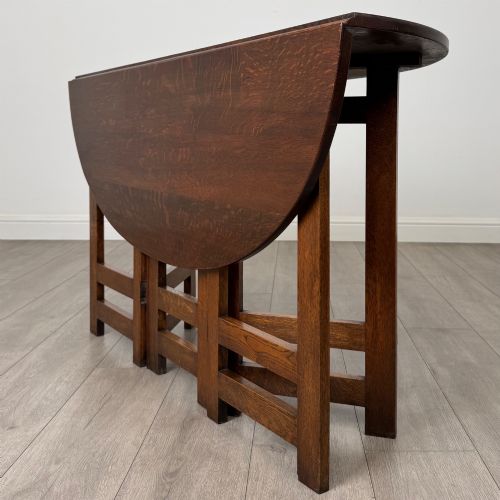 fig 6. An early 20th-century Arts and Crafts solid oak gateleg table featuring drop leaves and a geometric trestle base.