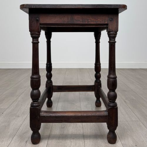 fig 2. An antique dark oak side table featuring a rectangular flat top, four turned legs, and a lower four-sided stretcher base.