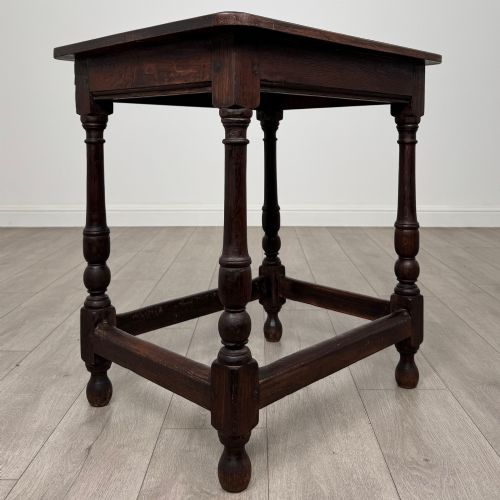 fig 3. An antique dark oak side table featuring a rectangular flat top, four turned legs, and a lower four-sided stretcher base.