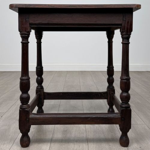 fig 4. An antique dark oak side table featuring a rectangular flat top, four turned legs, and a lower four-sided stretcher base.