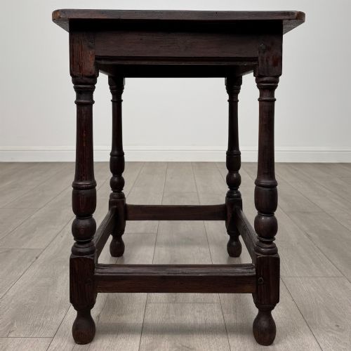 fig 6. An antique dark oak side table featuring a rectangular flat top, four turned legs, and a lower four-sided stretcher base.