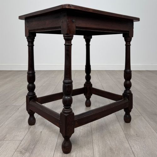 fig 7. An antique dark oak side table featuring a rectangular flat top, four turned legs, and a lower four-sided stretcher base.