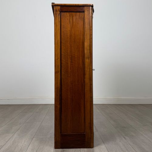 fig 7. A freestanding early 20th-century display cabinet featuring figured walnut veneers, a single glazed door with decorative astragal glazing bars, and internal wooden shelves.