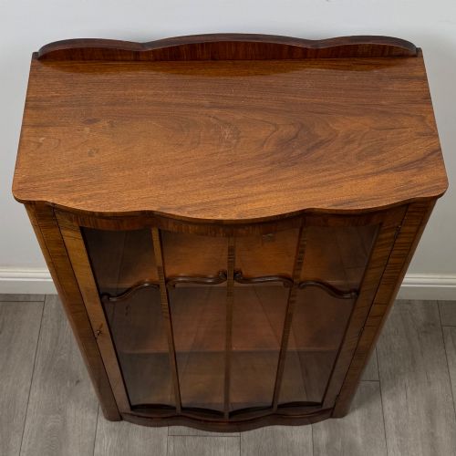 fig 9. A freestanding early 20th-century display cabinet featuring figured walnut veneers, a single glazed door with decorative astragal glazing bars, and internal wooden shelves.