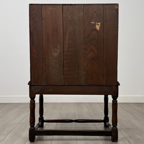 fig 5. A dark oak antique bureau featuring a slanted drop-front lid above two drawers, supported by turned legs and stretchers.