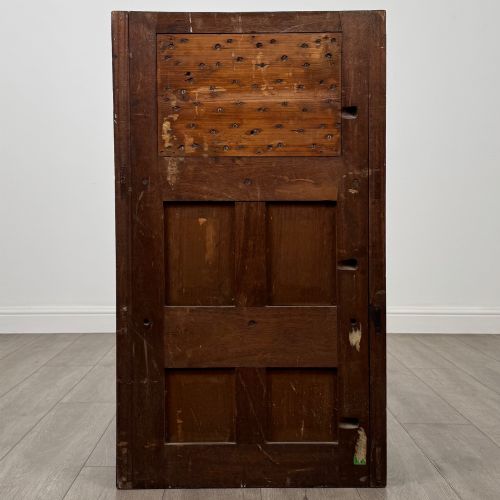 fig 5. A dark mahogany hall seat cabinet featuring a carved geometric back panel, decorative brass strap hinges, double cupboard doors, and finial corner posts.