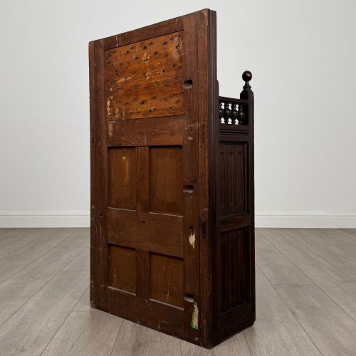 fig 6. A dark mahogany hall seat cabinet featuring a carved geometric back panel, decorative brass strap hinges, double cupboard doors, and finial corner posts.