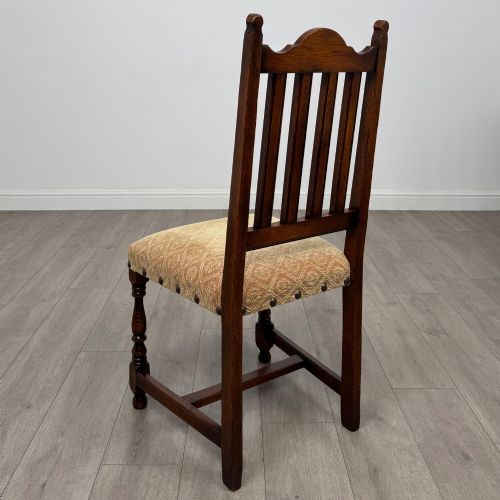 fig 3. A set of six dark oak dining chairs including two armchairs and four side chairs, featuring slat backs with carved crest details and patterned fabric seats.