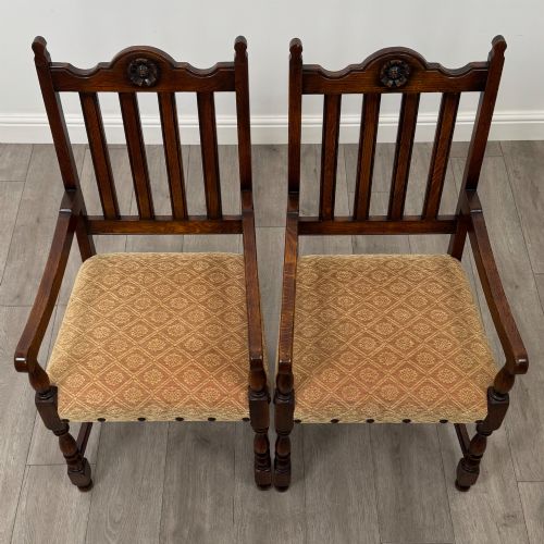 fig 7. A set of six dark oak dining chairs including two armchairs and four side chairs, featuring slat backs with carved crest details and patterned fabric seats.