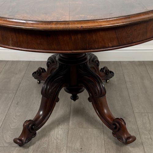 fig 4. A 19th-century Victorian circular rosewood breakfast table with a carved central pedestal column and four scroll legs with brass castors.