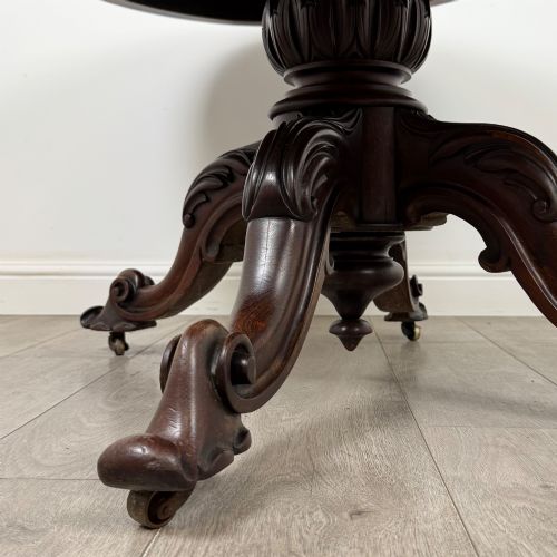 fig 6. A 19th-century Victorian circular rosewood breakfast table with a carved central pedestal column and four scroll legs with brass castors.