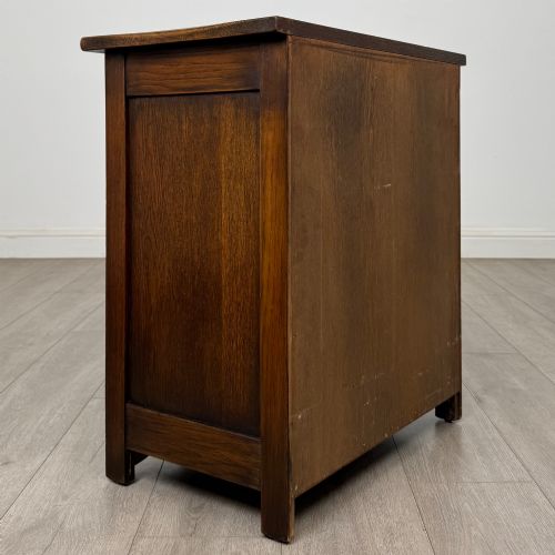 fig 3. A small early twentieth-century dark oak chest of drawers featuring three drawers with turned wooden knobs and a carved frieze top detail.