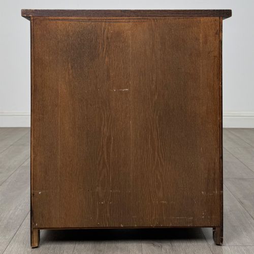 fig 4. A small early twentieth-century dark oak chest of drawers featuring three drawers with turned wooden knobs and a carved frieze top detail.