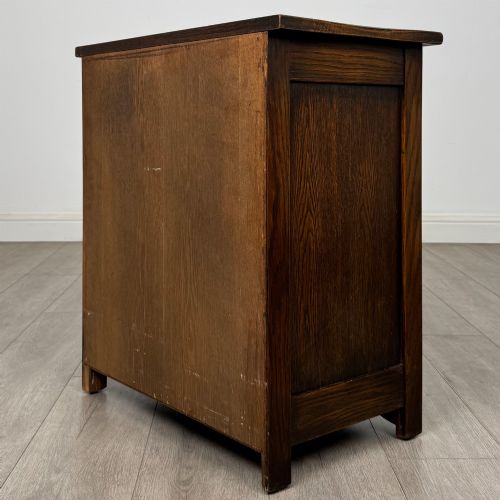 fig 5. A small early twentieth-century dark oak chest of drawers featuring three drawers with turned wooden knobs and a carved frieze top detail.