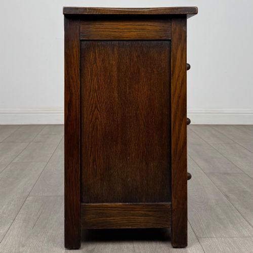 fig 6. A small early twentieth-century dark oak chest of drawers featuring three drawers with turned wooden knobs and a carved frieze top detail.