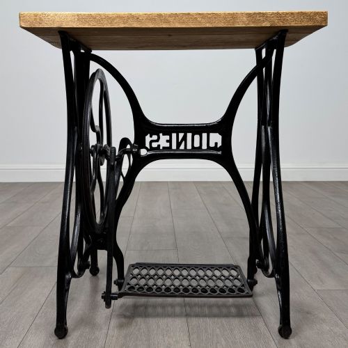 fig 3. An industrial side table featuring a black cast iron Jones treadle sewing machine base topped with a thick rectangular timber board.