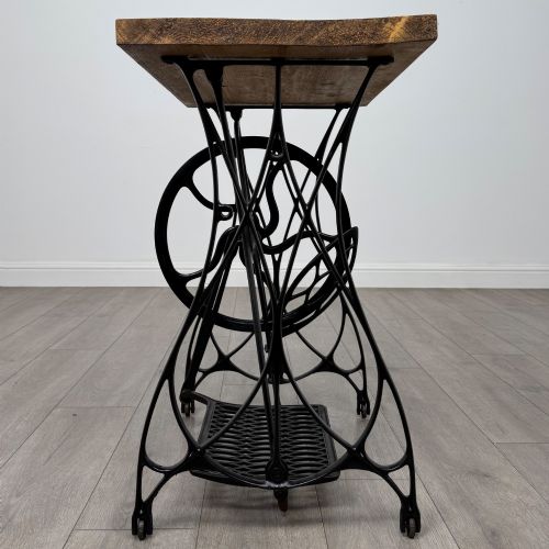fig 5. An industrial side table featuring a black cast iron Jones treadle sewing machine base topped with a thick rectangular timber board.