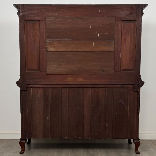 fig 5. An Arts and Crafts dark mahogany sideboard featuring an upper mirrored superstructure flanked by leaded glass cabinet doors above lower drawers and carved cupboards.