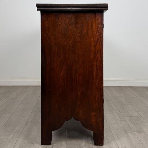 fig 7. A dark oak Gothic Revival sideboard featuring three central drawers with metal drop ring handles, flanked by two carved tracery panel doors with decorative iron latches.