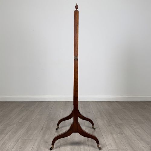fig 1. An Edwardian mahogany full-length cheval mirror featuring a rectangular tilting glass frame supported by a wooden upright stand with finials and splayed feet on brass castors.