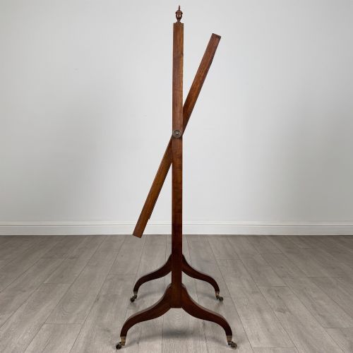 fig 2. An Edwardian mahogany full-length cheval mirror featuring a rectangular tilting glass frame supported by a wooden upright stand with finials and splayed feet on brass castors.